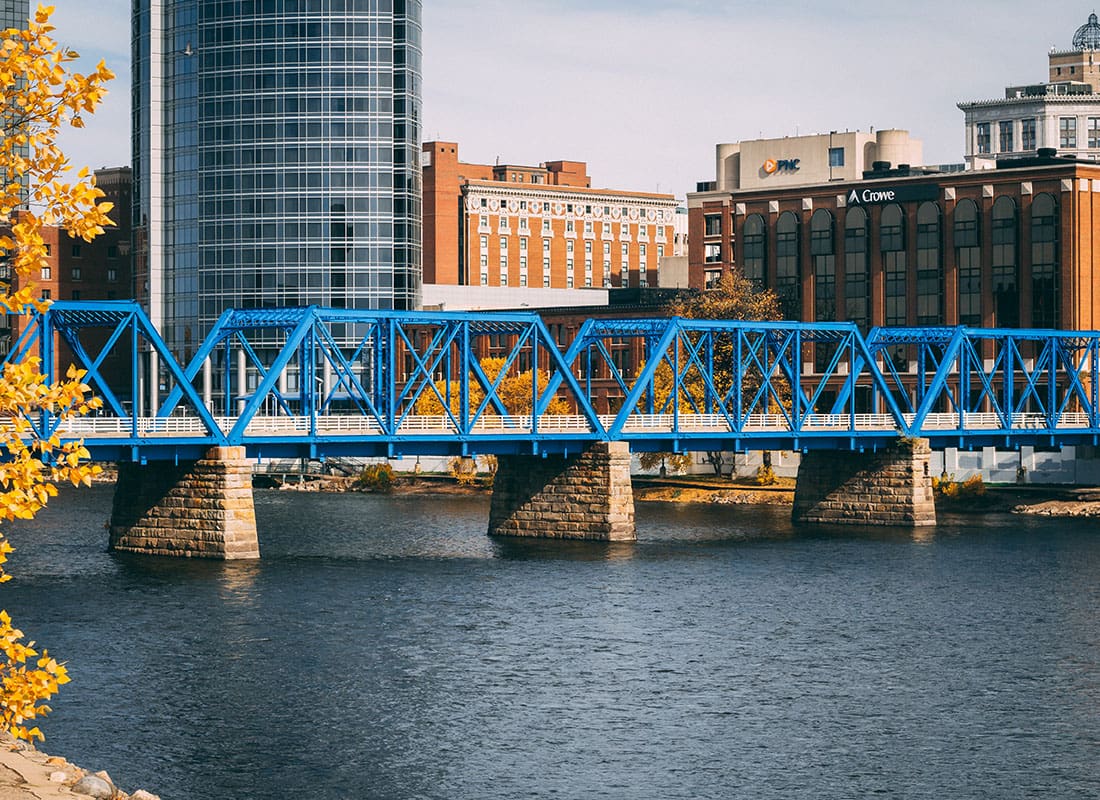About Our Agency - View of a Blue Steel Bridge Across the River in Downtown Grand Rapids Michigan with Commercial Buildings in the Background